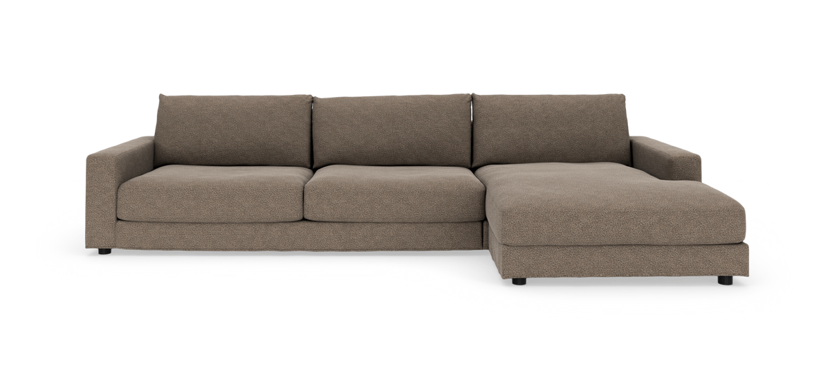 Brun hjørnesofa med chaiselong til højre, tre sæder og lave armlæn på hvidt frilæg.