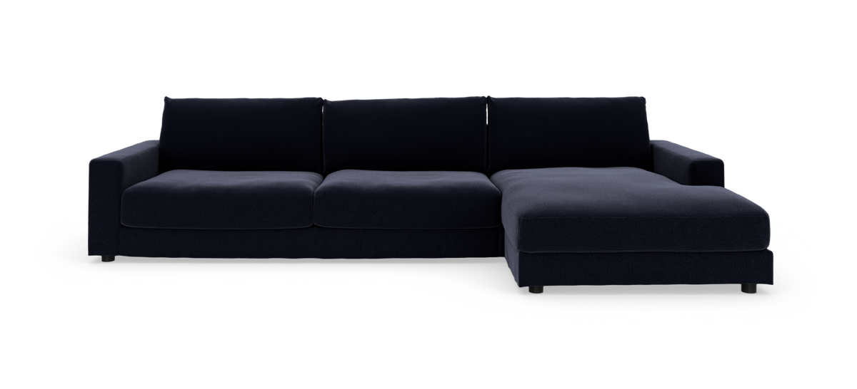 Mørkeblå L‑sofa med højre chaiselong, tre sæder, isoleret på hvid baggrund.
