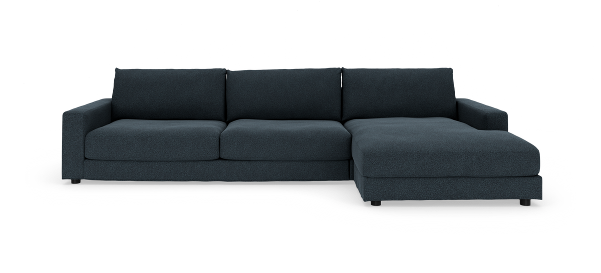Mørkeblå modulsofa med chaiselong i højre side, fotograferet lige forfra mod hvid baggrund i studiemiljø.
