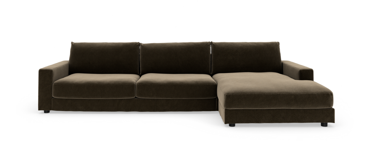 Brun hjørnesofa med chaiselong til højre i moderne, lavt stofdesign, frilagt på hvid baggrund.