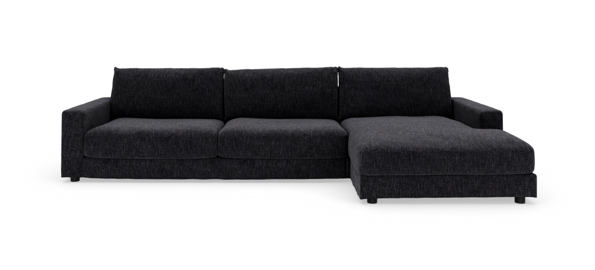 Mørkegrå hjørnesofa med chaiselong til højre, fotograferet lige for mod hvid baggrund.