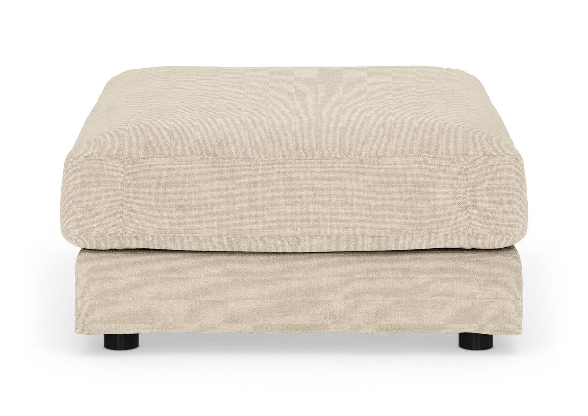 Beige stofpuf/fodskammel med lav profil og runde sorte ben, frilagt produktfoto set forfra.