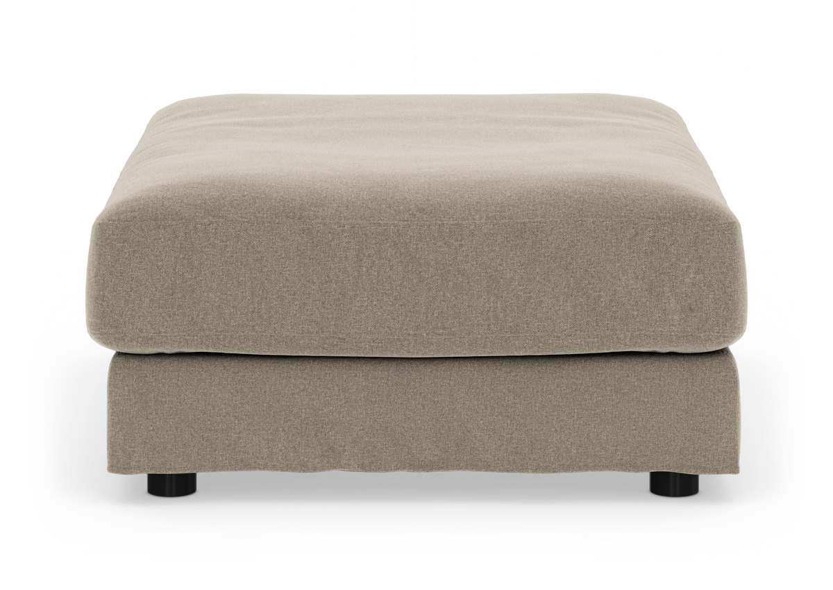 Beige stofbetrukket fodskammel/ottoman med sorte runde ben set forfra, frilagt på hvid baggrund.