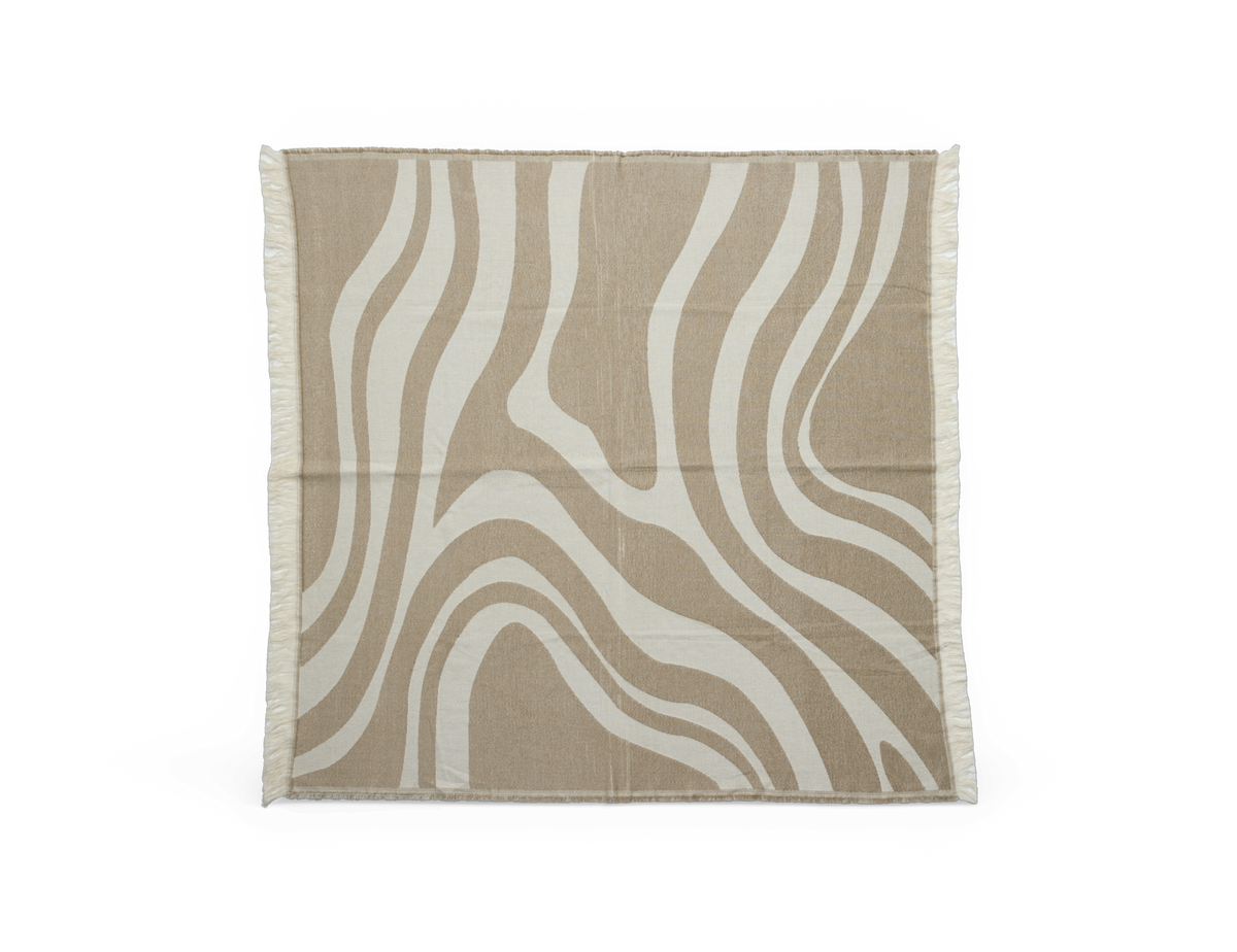 Beige og offwhite plaid/tæppe med bølget, organisk mønster og frynsede kanter.