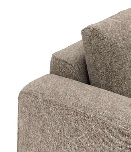 Nærbillede af beige stofsofa med armlæn og ryghynde, isoleret på sort baggrund.