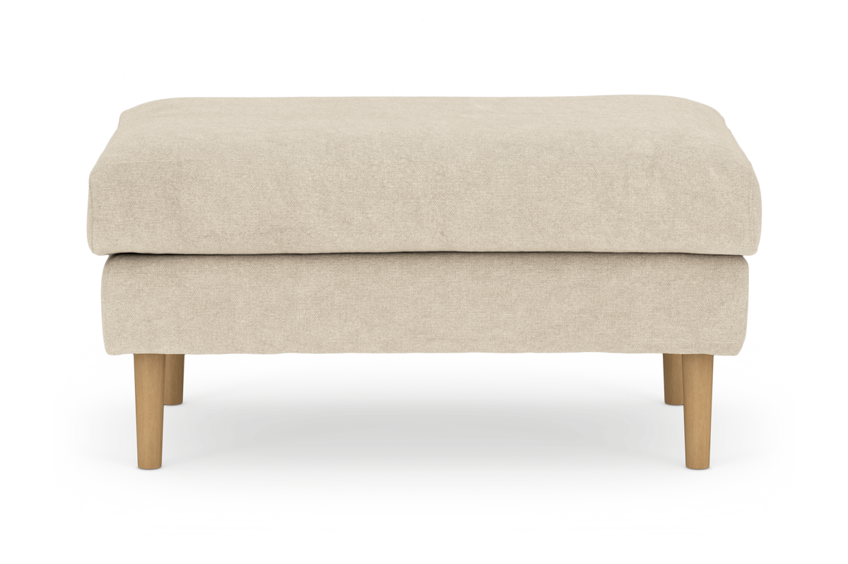 Beige polstret skammel/ottoman med runde træben, frilagt på hvid baggrund.