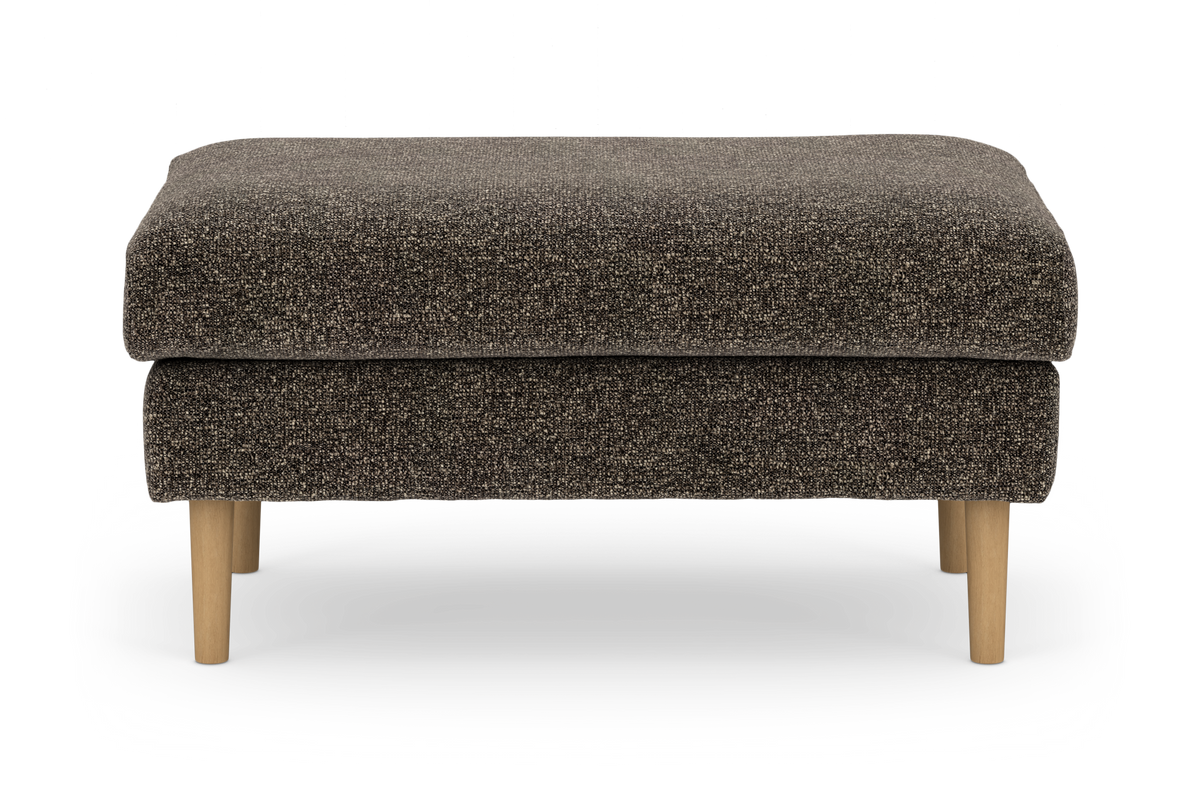 Brun, tekstureret pouf/fodskammel med lyse træben, frilagt på hvid baggrund.