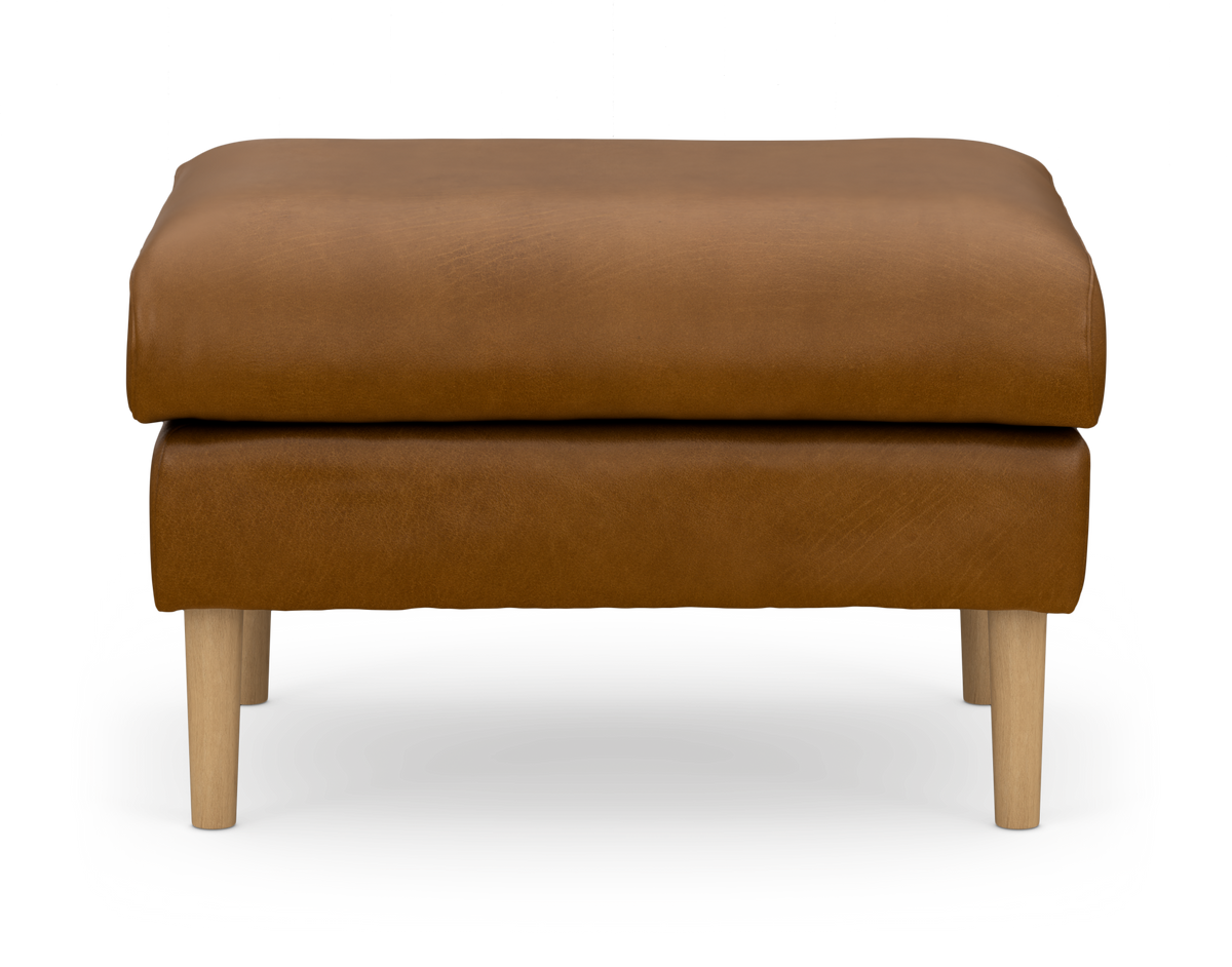 Brun læderpuf/ottoman med lyse træben, frontalt mod hvid baggrund.