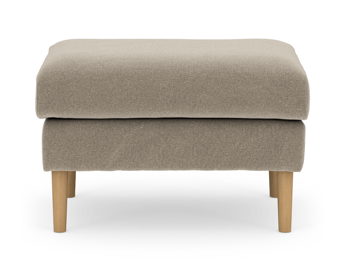 Beige puf/skammel med stofbetræk og lyse træben, frilagt på hvid baggrund.