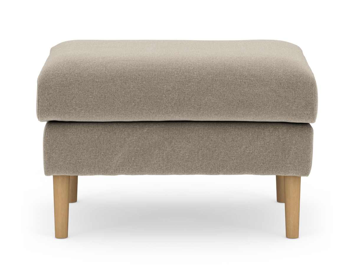 Beige polstret fodskammel/puf i stof med runde træben, frilagt på hvid baggrund.