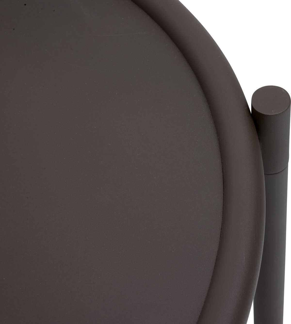 Close-up af rund mørk bakke-/bordkant med cylinderformet detalje.