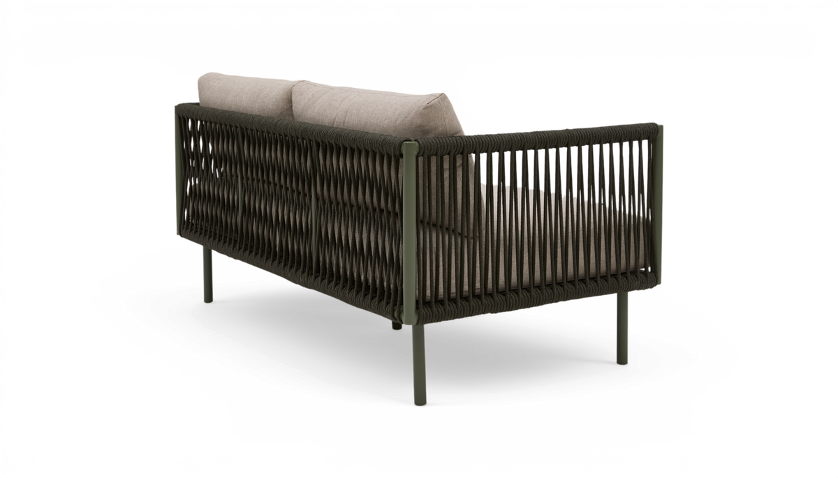 Sofa med mørk flettet ramme og beige puder, set bagfra i studie.