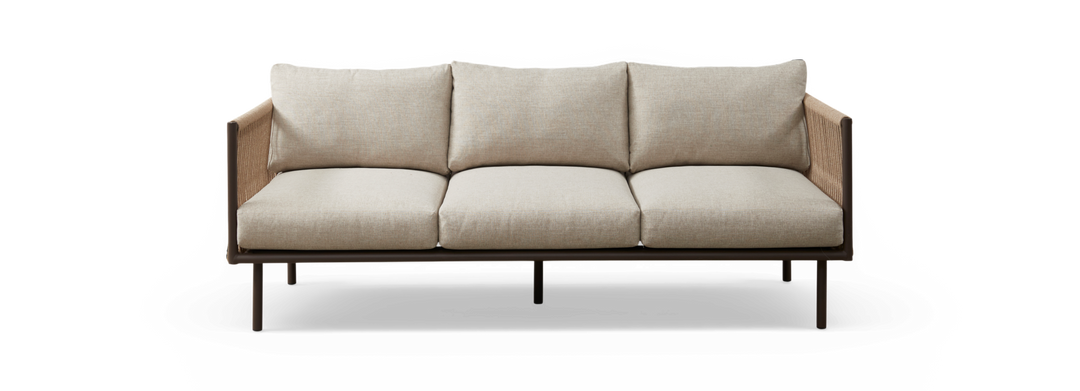 Beige 3-personers sofa med stofbetræk, brun ramme og flettede sidepaneler, frilagt på sort baggrund set forfra.