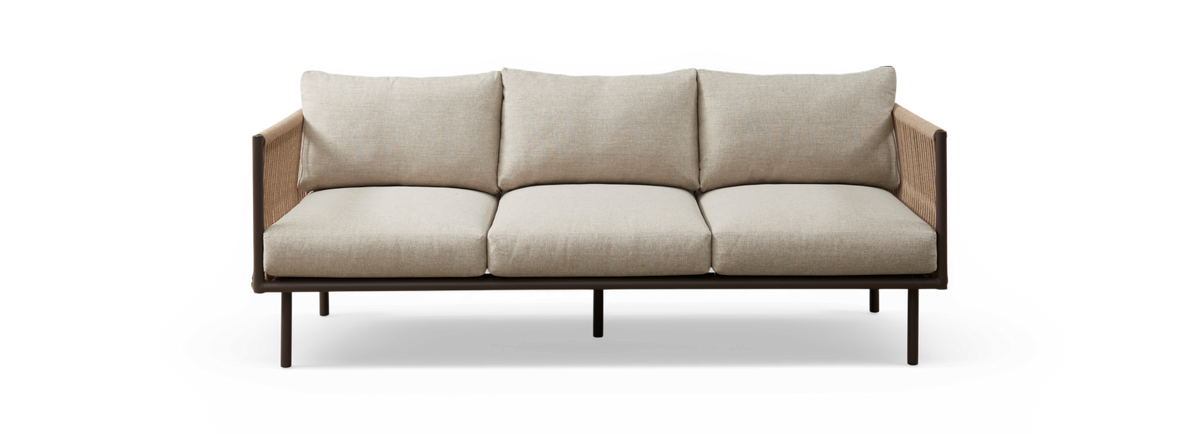 Beige 3-personers sofa med stofbetræk, brun ramme og flettede sidepaneler, frilagt på sort baggrund set forfra.