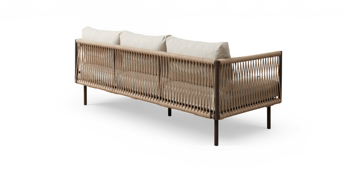 Lang tresæders sofa med beige puder og flettet reb-ramme, set skråt bagfra på hvid baggrund.