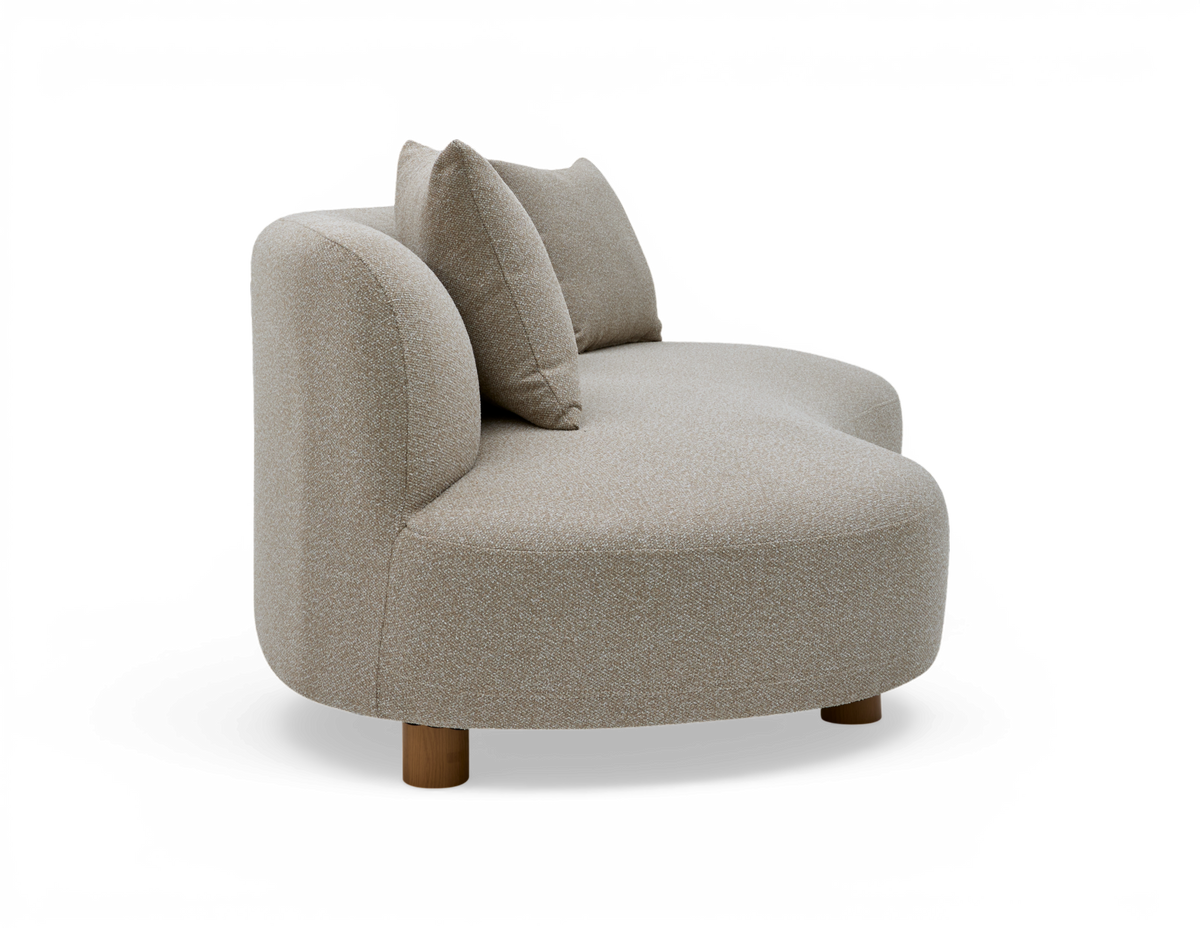 Beige, rundet to-sæders sofa med to puder og træben, fotograferet på hvid baggrund.