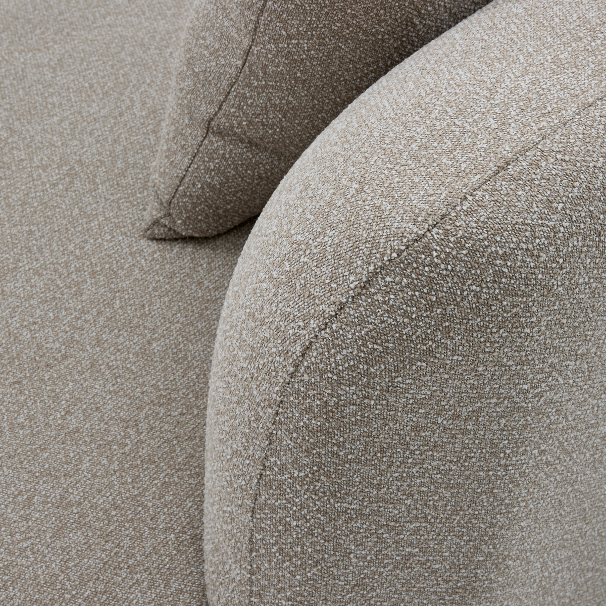 Nærbillede af beige bouclésofa med afrundet armlæn og pude.
