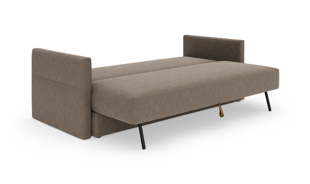 Beige sovesofa uden ryglæn, slået ud som seng med sorte ben, frilagt på hvid baggrund.