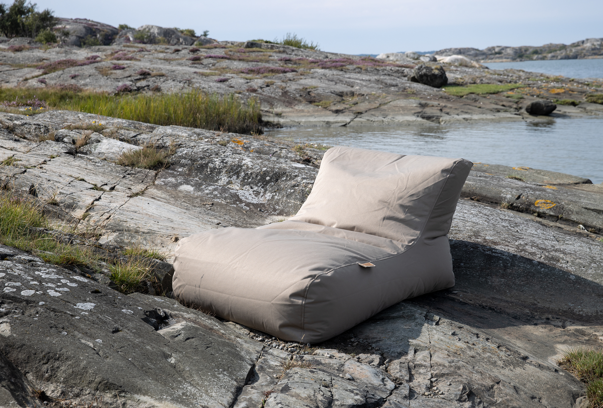 Beige loungemøbel på klippe ved kysten.