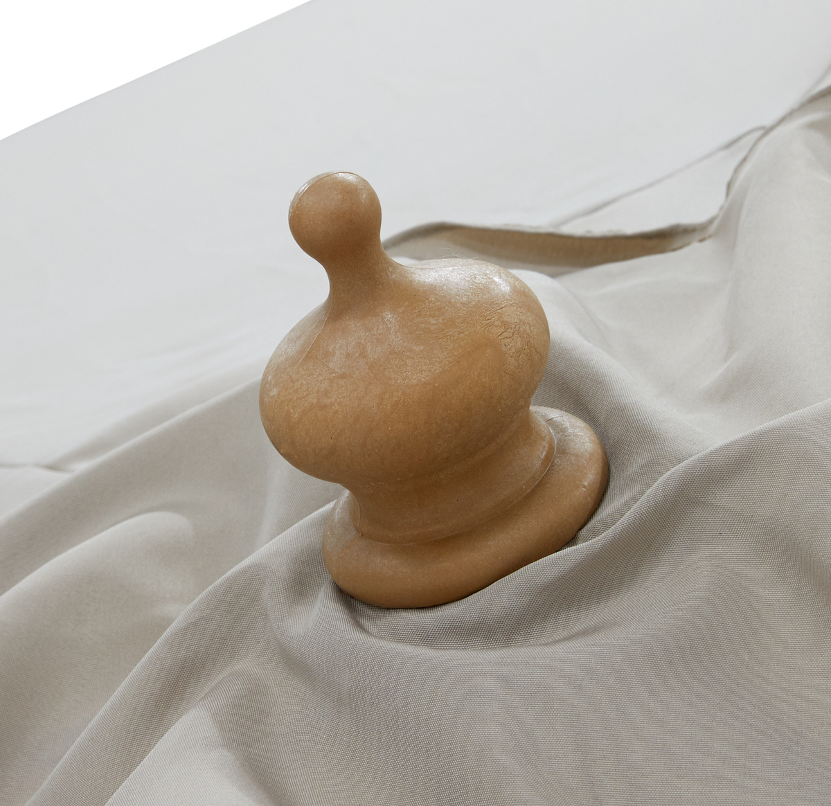 Lille rund træknop på lyst beige stof, close-up.
