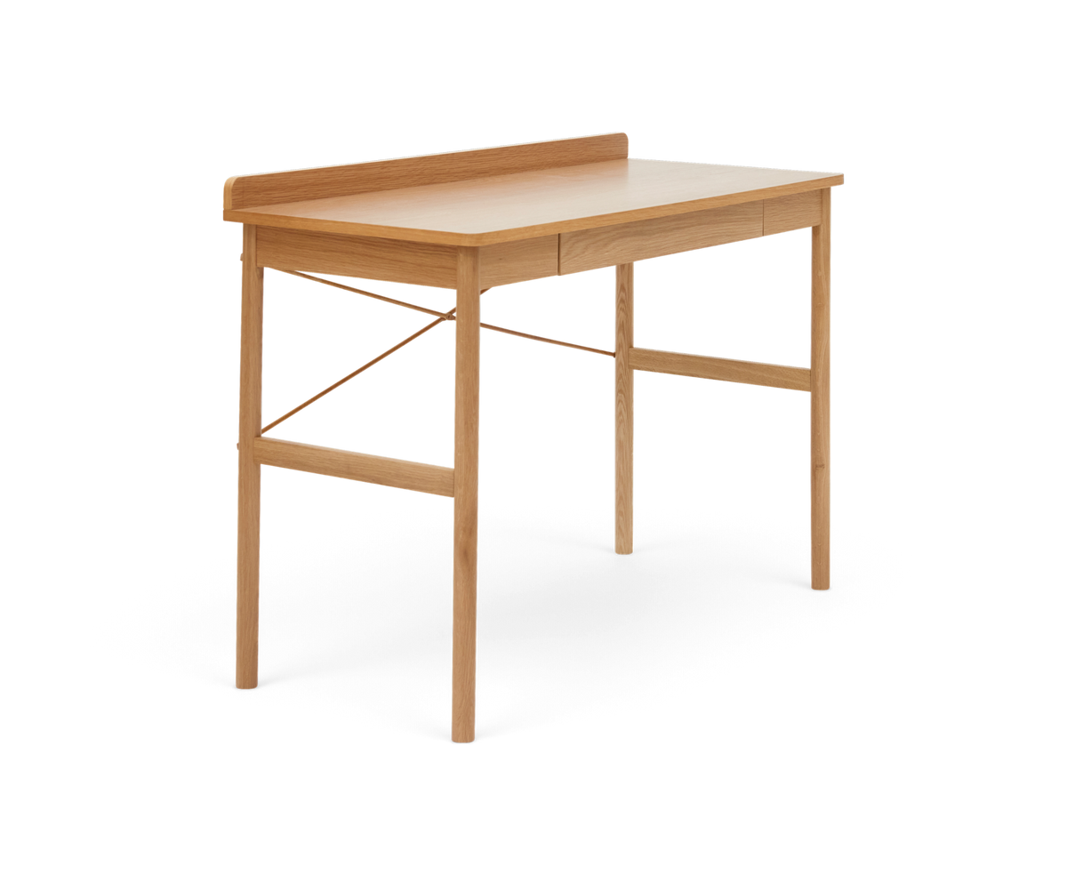 Skrivebord i lys eg med smal bagkant og skuffe, fritlagt produktfoto i trekvartsvinkel.