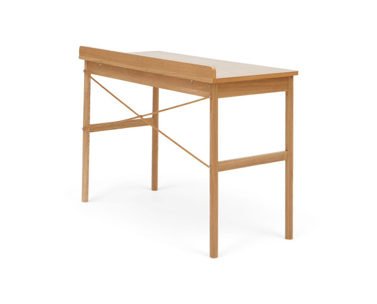 Smal skrivebord/konsolbord i lys eg med afrundet bagkant og krydsede afstivere, fritlagt på hvid baggrund.