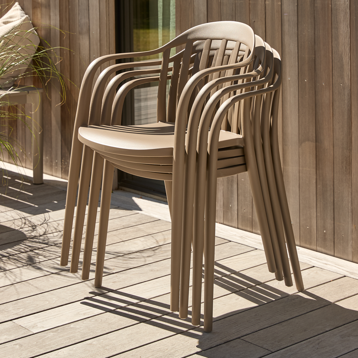 Stablede beige udestole på en træterrasse i sollys.