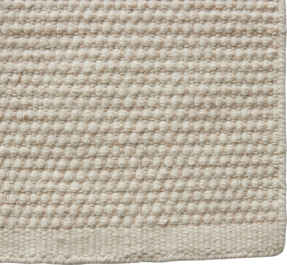 Nærbillede af beige vævet tæppe med nubret struktur og kantafslutning.