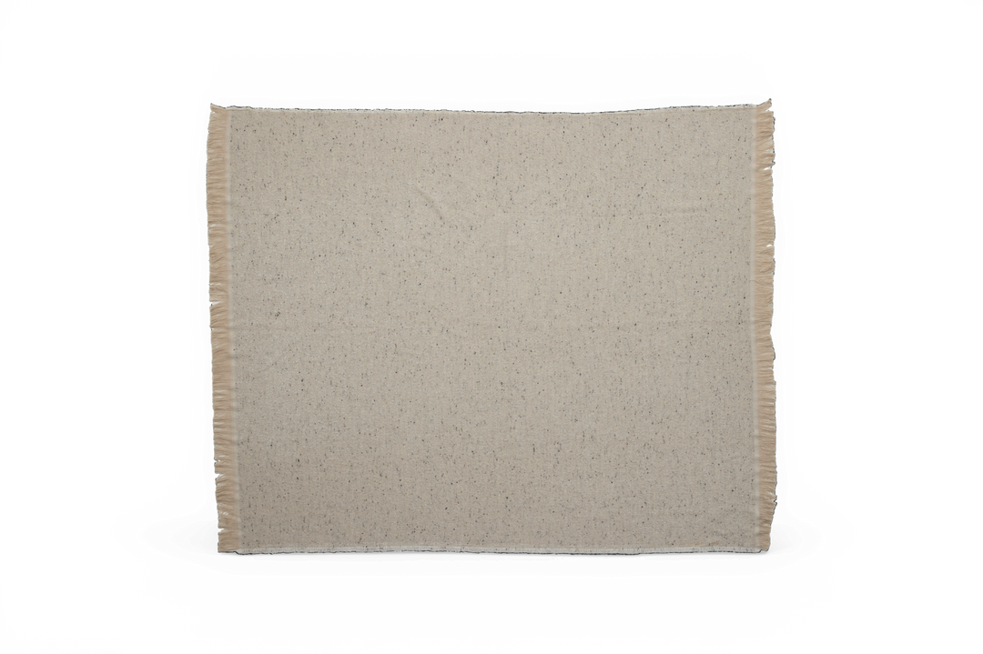 Beige meleret plaid med frynser i siderne mod sort baggrund.