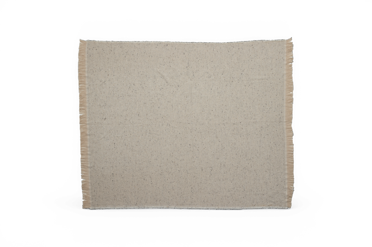 Beige meleret plaid med frynser i siderne mod sort baggrund.