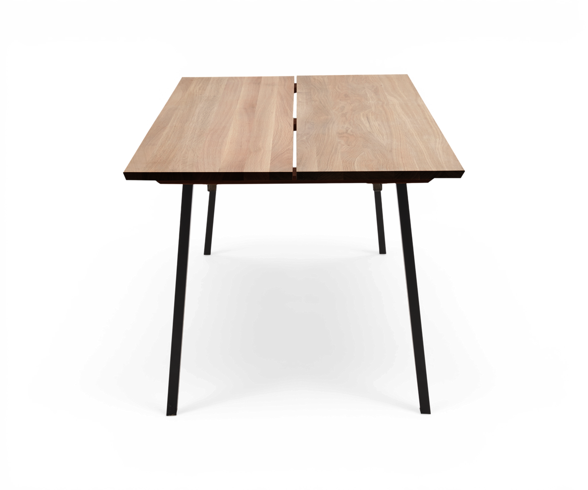 Rektangulært spisebord med lys træbordplade i to planker og sorte skråtstillede metalben, set forfra på hvid baggrund.