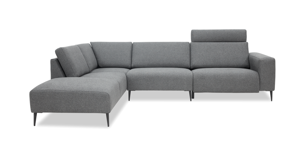 Grå modulsofa i L‑form med chaiselong og høj nakkestøtte på det ene sæde, slanke sorte ben.