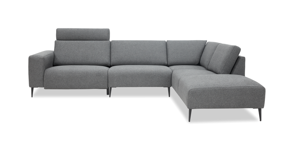 Grå hjørnesofa med chaiselong til højre, slanke ben og justerbar nakkestøtte, frontvisning.