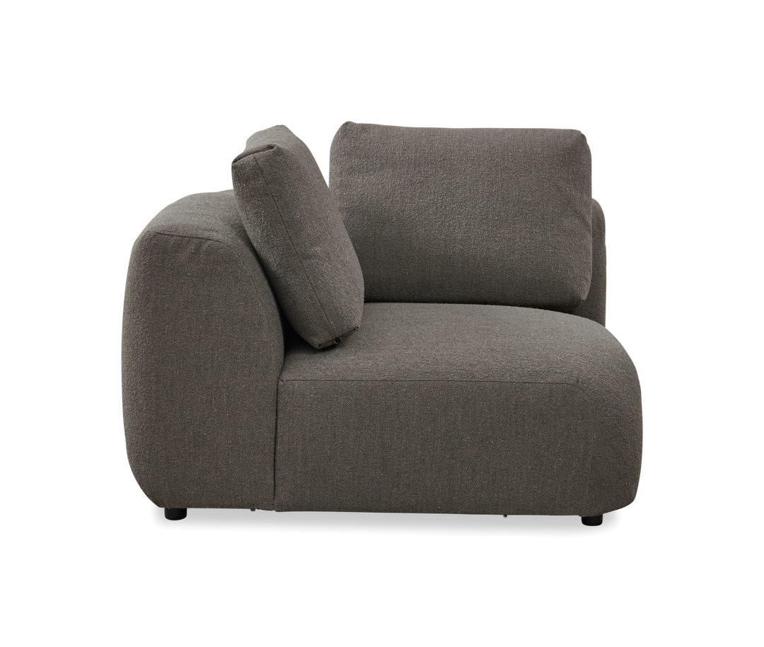 Grå modulsofa i stof med rundet venstremodul og to ryghynder, frilagt på hvid baggrund.