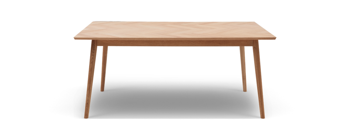 Rektangulært spisebord i lys eg med sildebensmønstret bordplade og slanke, tilspidsede ben.