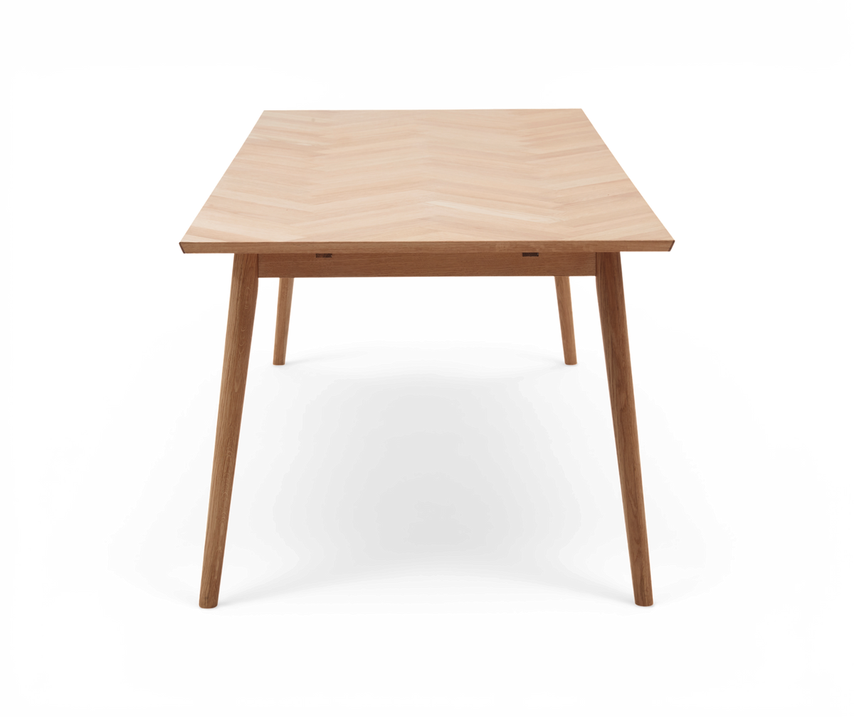 Rektangulært spisebord i lyst træ med skrå ben, frontvy.