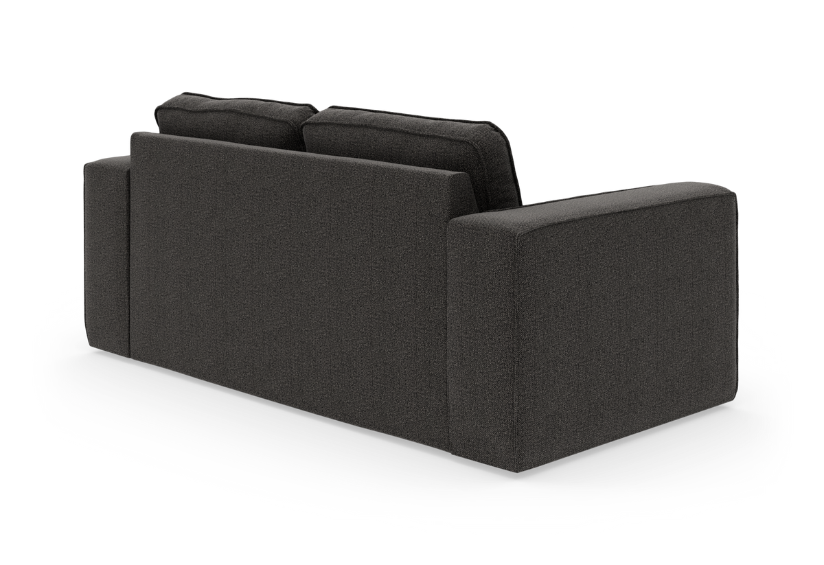 Mørkegrå 2–3-personers sofa set bagfra i trekvart vinkel med brede armlæn og løse ryghynder.