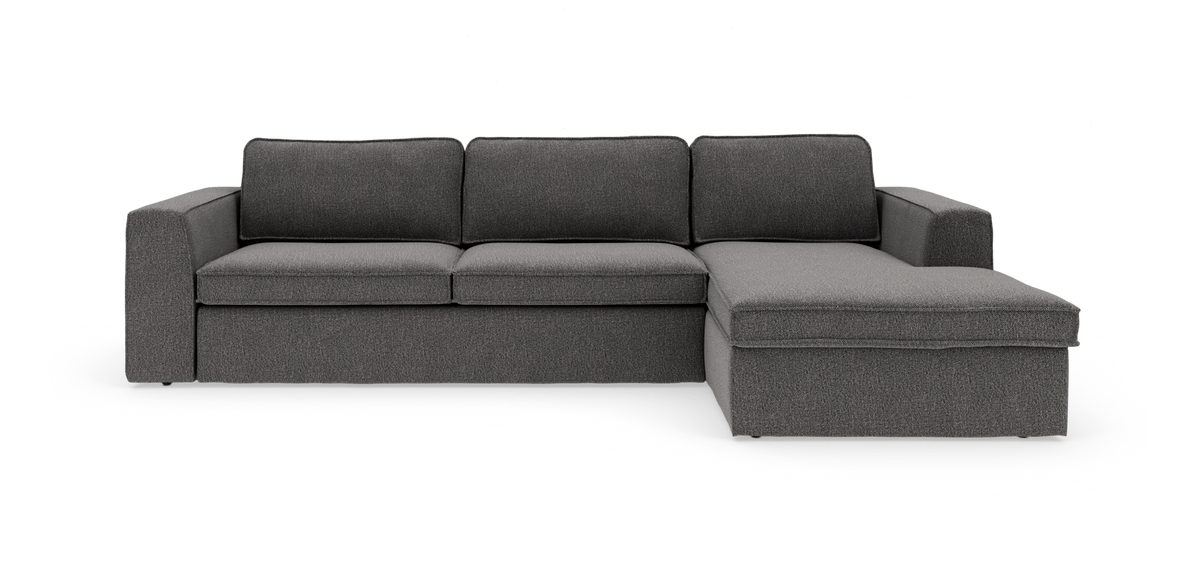 Mørkegrå L‑formet hjørnesofa med chaiselong til højre, tre sæder og brede armlæn, frilagt på hvid baggrund.