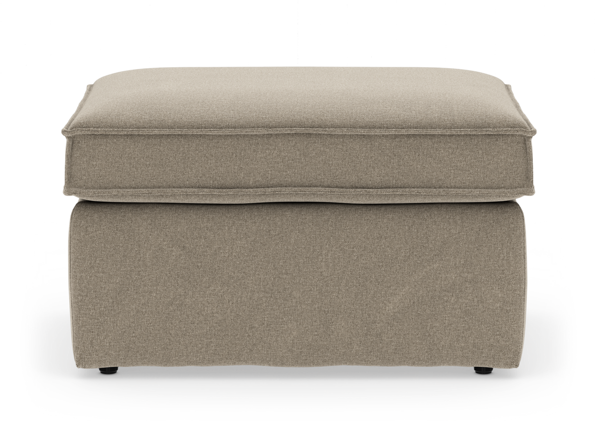 Beige stofbetrukket skammel/puf med blød bokspude og skørt bund, frilagt på hvid baggrund.