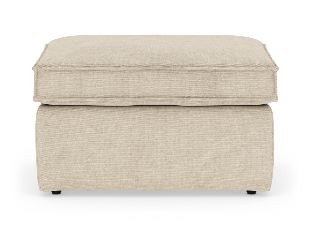 Beige polstret ottoman/skammel med blød pudetop, frilagt på hvid baggrund.
