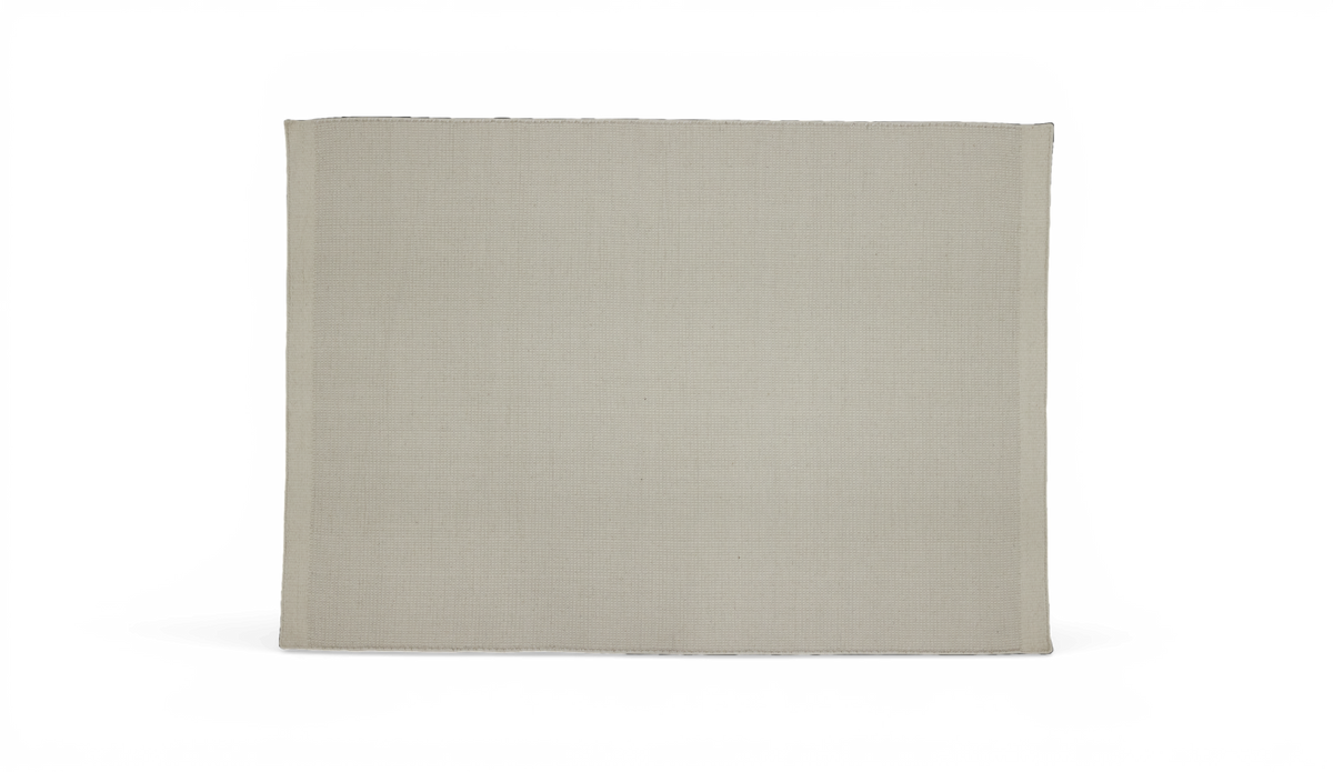 Beige vævet stofserviet med enkel kant, fotograferet fladt mod sort baggrund.