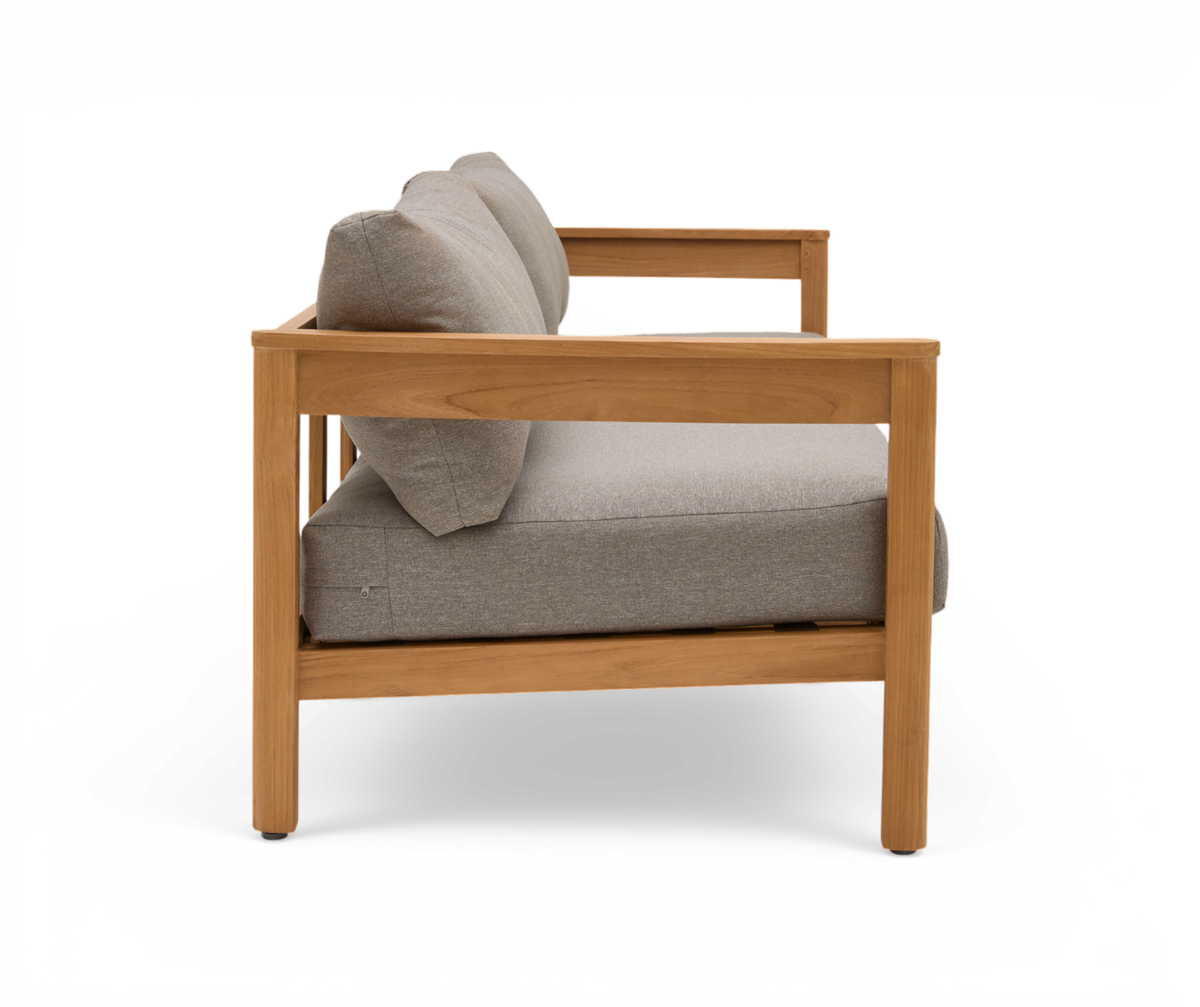 Sideview af en lænestol/sofa med lysegrå hynder og ramme i lyst træ, frilagt på hvid baggrund.