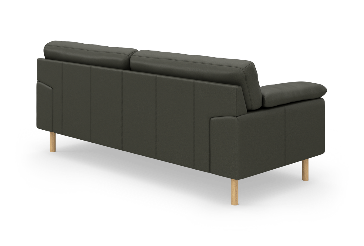 Mørkegrøn sofa set bagfra i vinkel på lyse træben, frilagt studieopstilling.