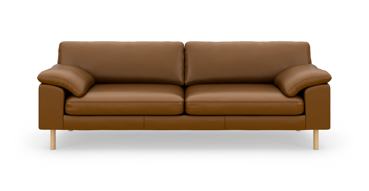Brun lædersofa med bløde armlæn og træben, frilagt på hvid baggrund.