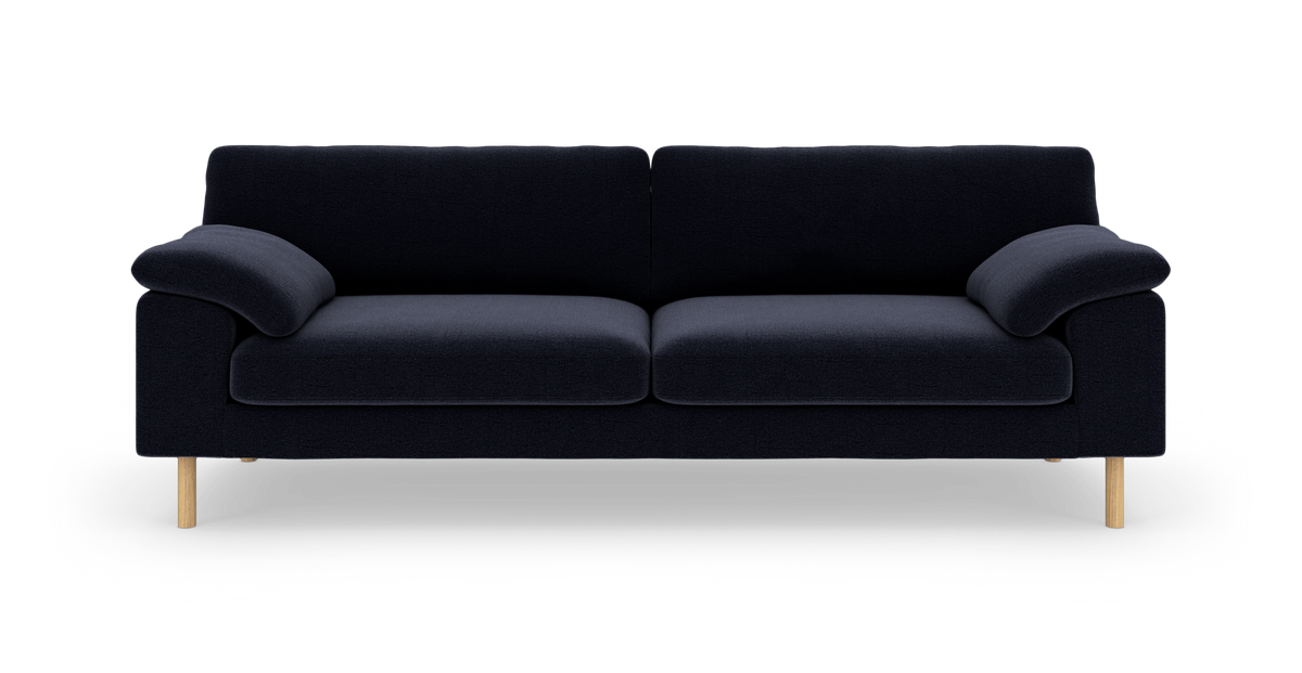 Mørkeblå sofa med to siddehynder, bløde armlæn og lyse træben på hvid baggrund.