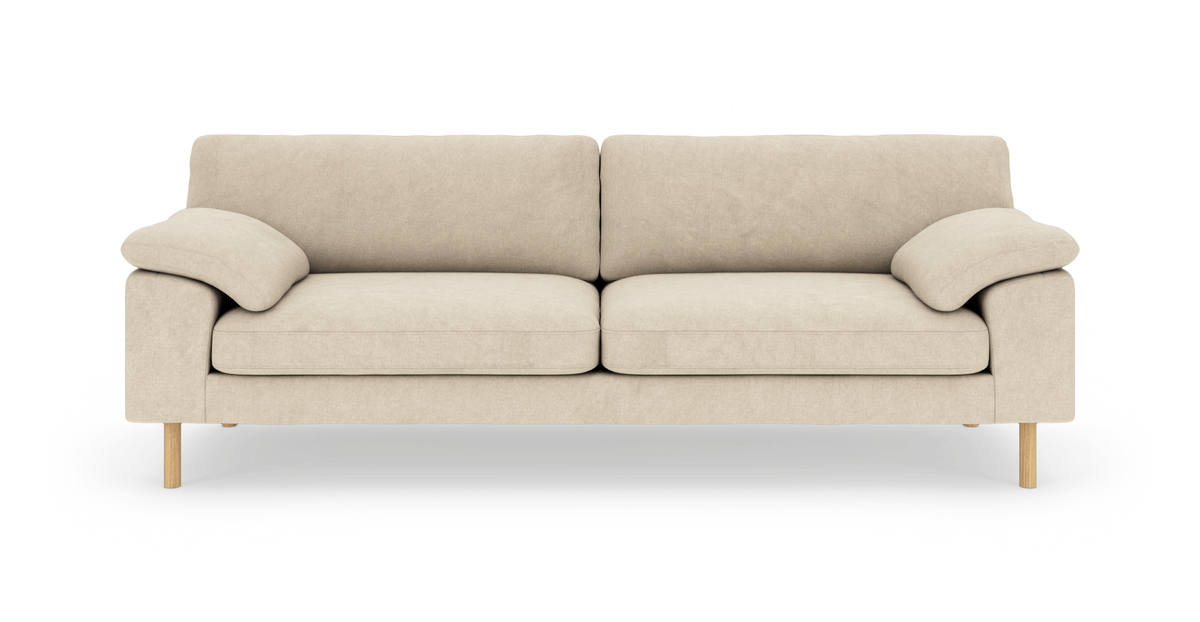Beige sofa med bløde armlæn og træben på hvid baggrund.
