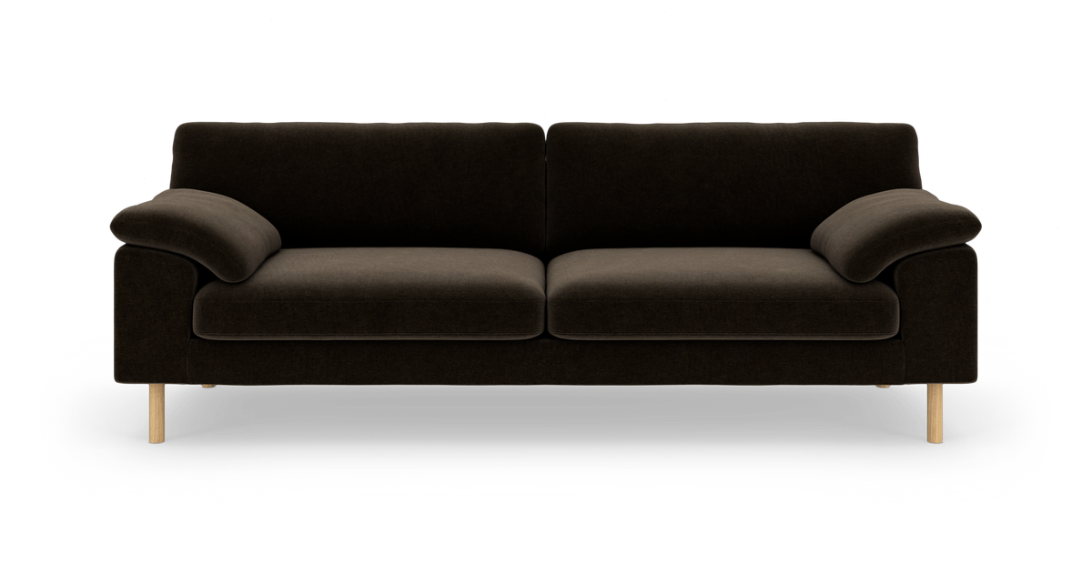 Mørkebrun sofa med afrundede armlæn og lyse træben, frilagt på hvid baggrund.