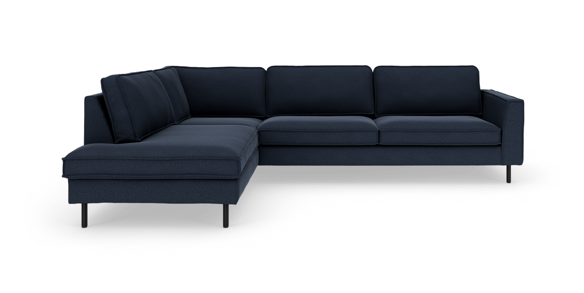 Mørkeblå L‑sofa med venstrevendt chaiselong, slanke sorte ben og moderne design på hvid baggrund.