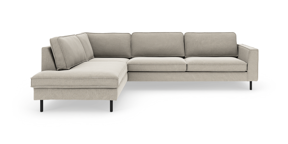 L-formet hjørnesofa med venstre chaiselong i lys beige stof og slanke sorte metalben, frilagt på hvid baggrund.
