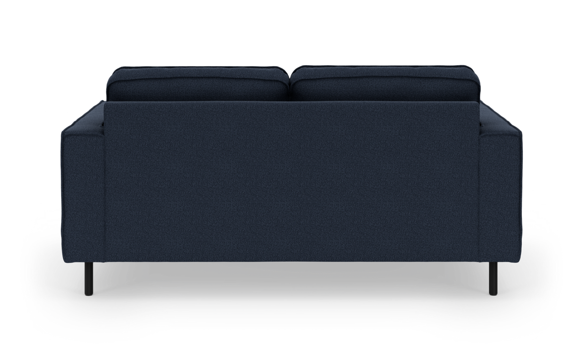 Mørkeblå tresæders sofa set lige bagfra med to ryghynder og slanke sorte ben.